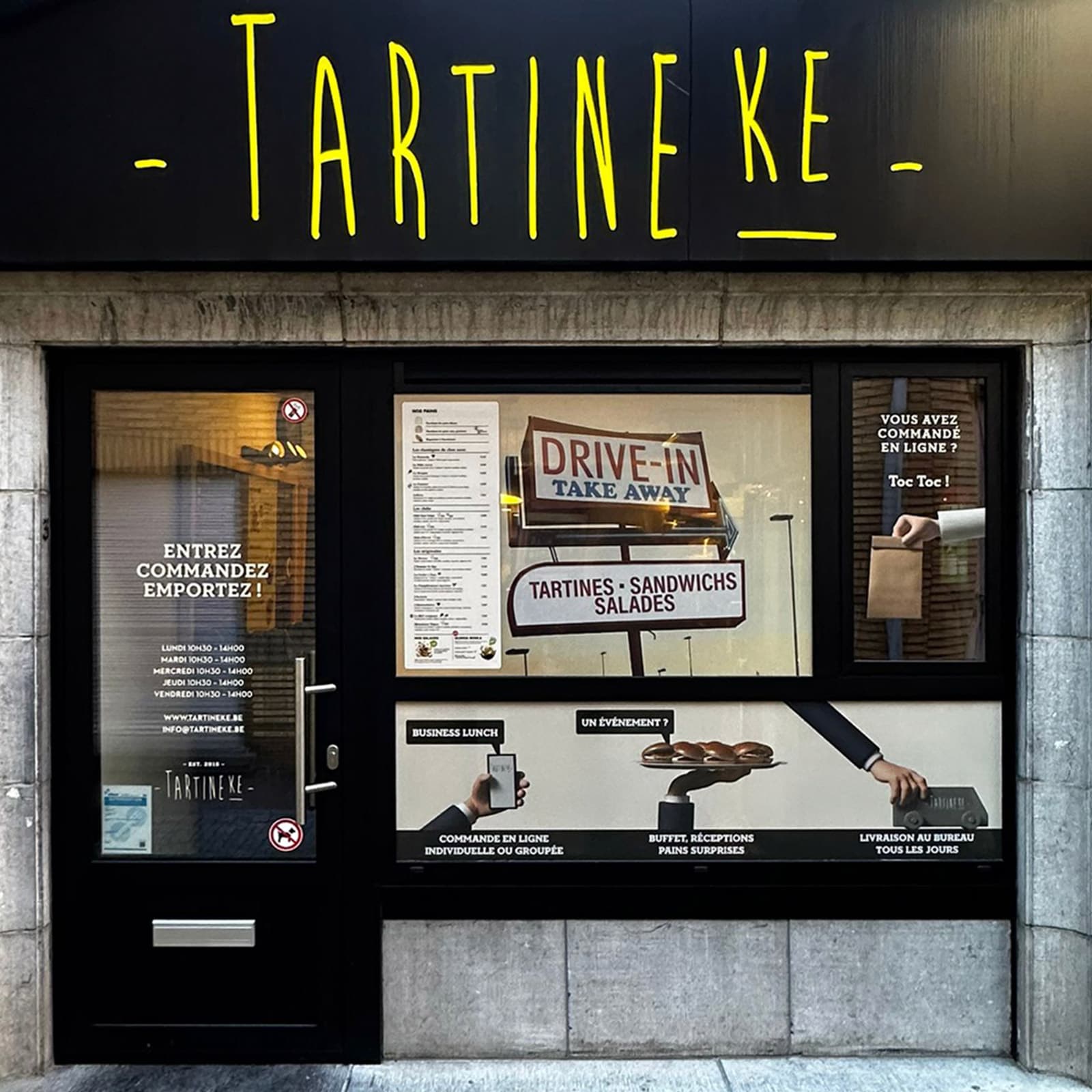 Façade du commerce Tartineke à Wavre avec vitrine illustrée, signalétique graphique et mise en avant de l’offre sandwichs.