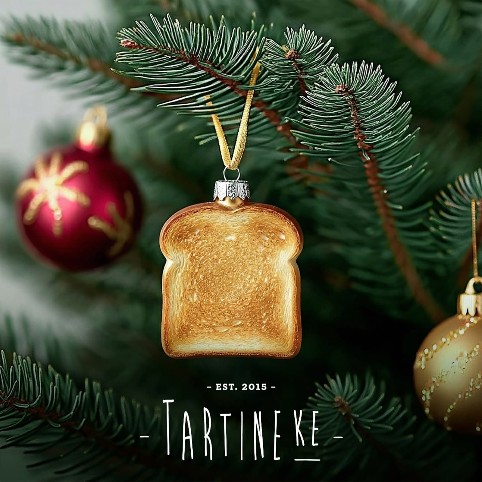 tartineke13Décoration de Noël Tartineke représentant une tranche de pain suspendue dans un sapin, clin d’œil festif à l’univers de la marque.